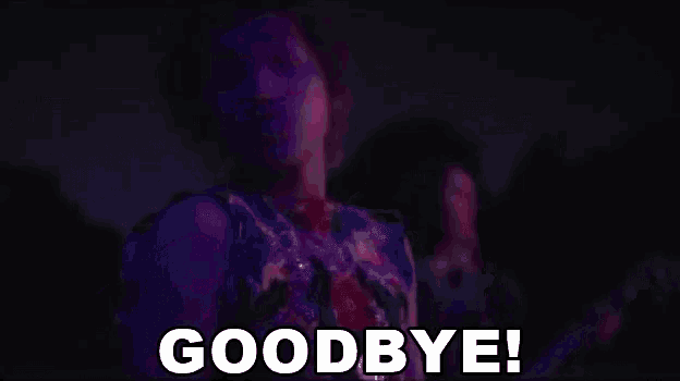 a man in a purple shirt is saying goodbye in a dark room .