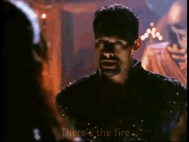 a man with a beard is talking to another man with the words there 's the fire below him
