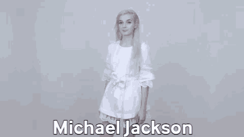 a woman in a white dress is standing in front of a michael jackson sign