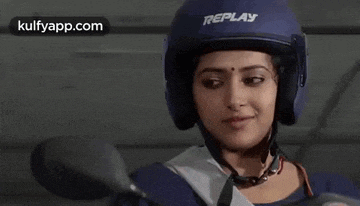 a woman wearing a replay helmet is smiling while riding a motorcycle .