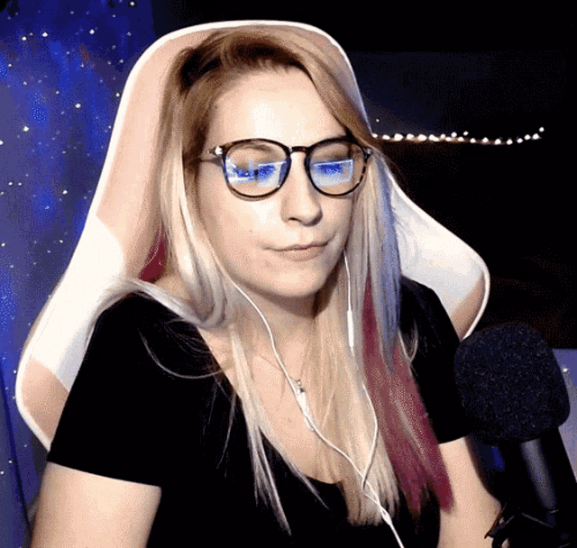 a woman wearing glasses and headphones sits in a gaming chair