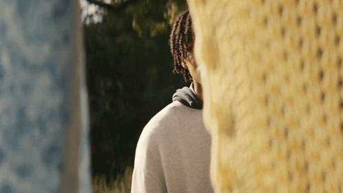 a man with dreadlocks is standing in front of a yellow blanket