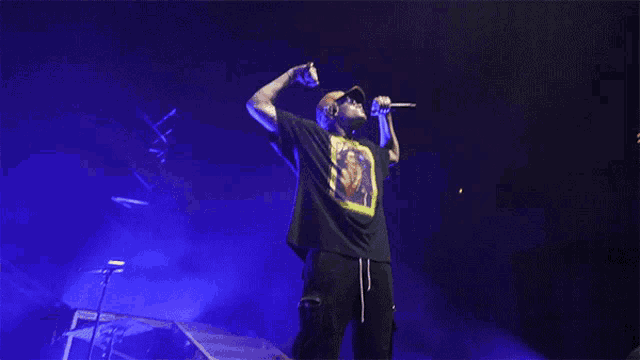 a man singing into a microphone wearing a t-shirt that has a picture of a man on it