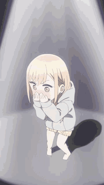 a little girl is standing in front of a spotlight and covering her mouth with her hands .