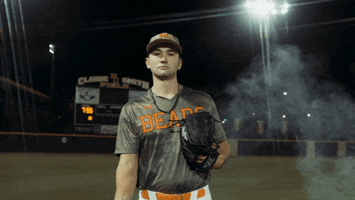 a baseball player wearing a bears jersey stands in front of a scoreboard