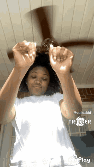 a woman is playing with a ceiling fan and a triller logo is visible