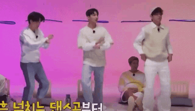 a group of men are standing next to each other on a stage and dancing .