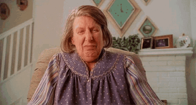 an elderly woman is sitting in a chair with her eyes closed .