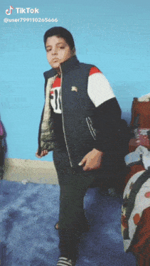 a boy is standing in front of a blue wall with tiktok written on the bottom right corner