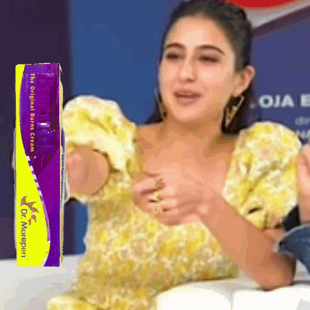 a woman in a yellow dress is holding a box of dr. murpen