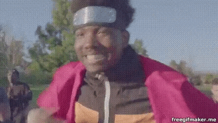 a man is wearing a headband and a pink jacket and is smiling .