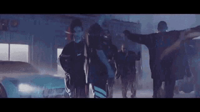 a group of people are standing next to each other in a dark room in front of a car .