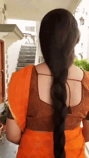a woman with very long hair is wearing an orange top