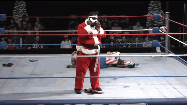 a wrestler in a santa suit stands in a ring