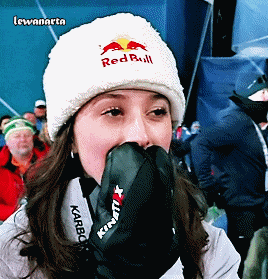 a woman wearing a red bull hat covering her mouth with her hand