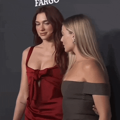 two women standing next to each other in front of a sign that says fargo on it