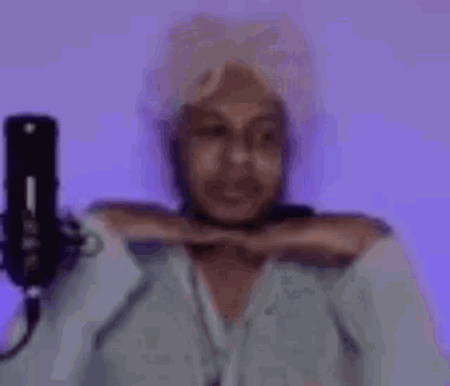 a man is taking a selfie in front of a microphone while wearing a wig .
