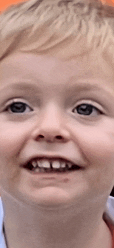 a close up of a young boy 's face with a smile on his face