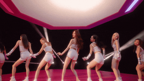 a group of women in white shorts are dancing on a pink stage