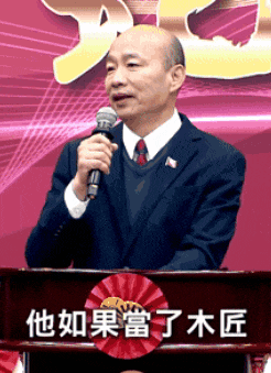 a man in a suit stands at a podium holding a microphone with chinese writing on it