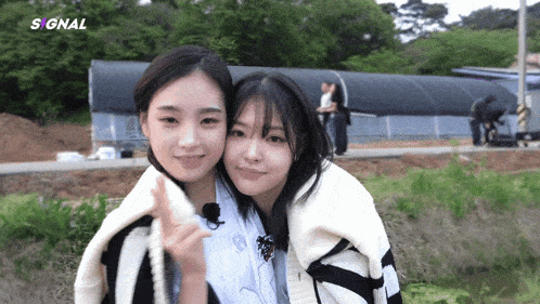 two girls are posing for a picture and the word signal is on the bottom right