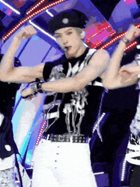 a man is flexing his muscles on a stage while wearing a beret and a black shirt .