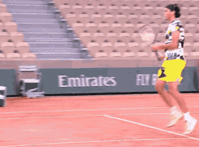 a man in yellow shorts is playing tennis on a red court