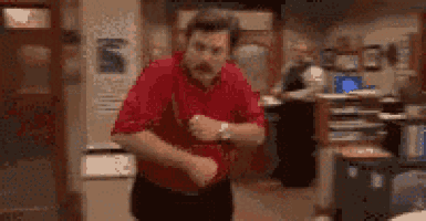 a man in a red shirt is dancing in a room in an office .