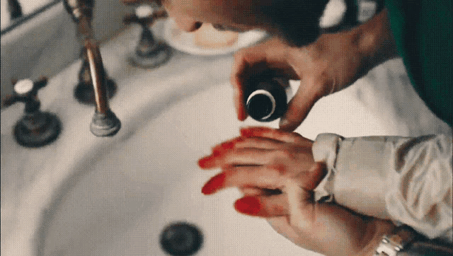 a person is washing their hands in a sink with blood on them