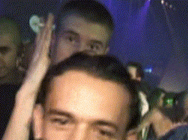 a man wearing headphones looks at the camera while another man looks on