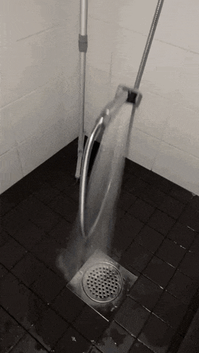 a mop is being used to clean the drain in a bathroom