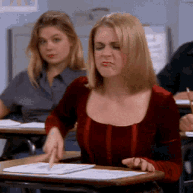 a woman in a red top sits at a desk