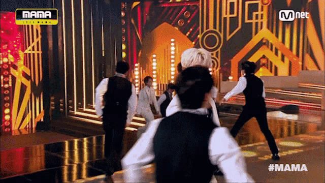 a group of men are dancing on a stage with a mnet logo in the background