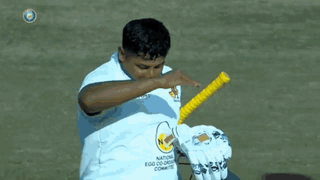 a man in a white shirt that says nc is holding a bat
