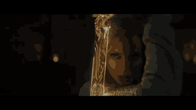 a close up of a woman holding a sword in her hand in a dark room .