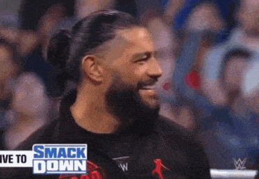roman reigns is smiling in front of a crowd during a smack down live event .