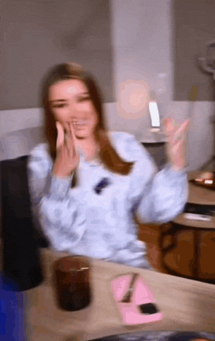 a blurry picture of a woman sitting at a table with her hand on her face
