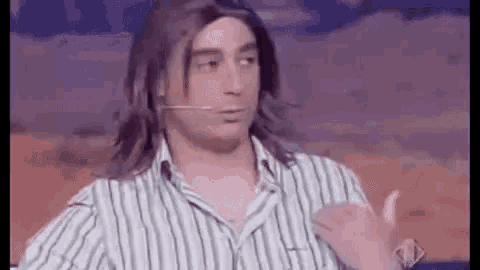 a man with long hair is wearing a striped shirt and a microphone on his neck .