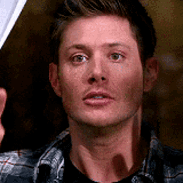 a close up of a man 's face with a plaid shirt on .