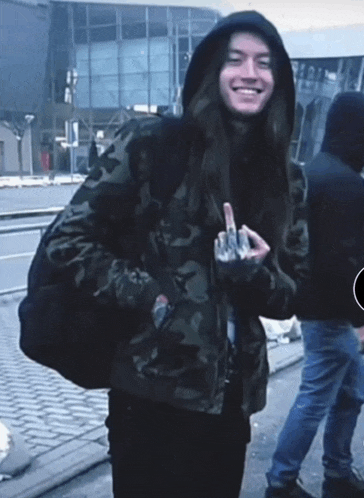 a man wearing a camo jacket and a hood giving the middle finger