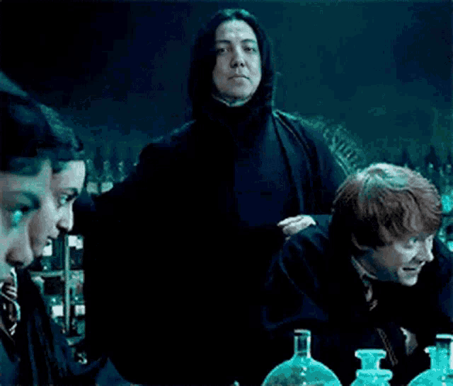 a group of people are sitting at a table with bottles of potions in front of them .