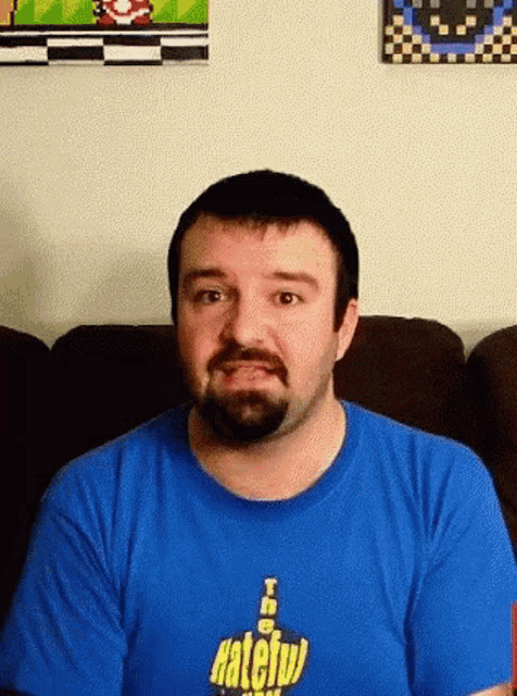 a man with a beard is wearing a blue shirt that says hateful on it
