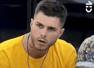 a man wearing a yellow shirt and ear buds looks surprised