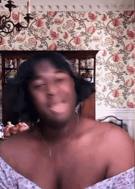 a shirtless man is making a funny face in front of a floral wallpaper .