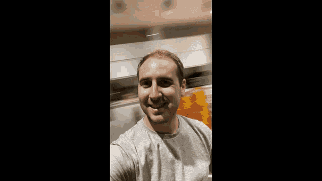 a man in a grey shirt is taking a selfie