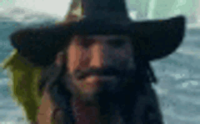 a man with long hair and a beard is wearing a hat and holding a fish in his hand .