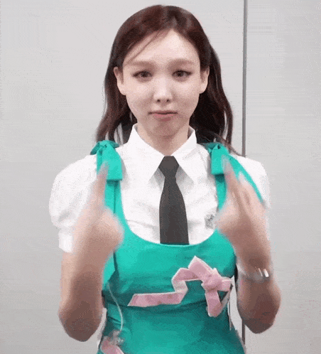 a woman wearing a white shirt and a green apron is making a funny face