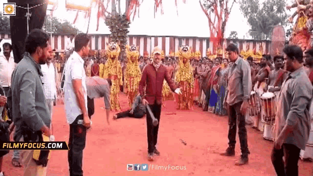 a man is holding a bat in front of a crowd of people with filmyfocus.com written on the bottom