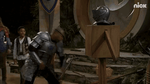 a man in armor is standing in front of a wooden box .