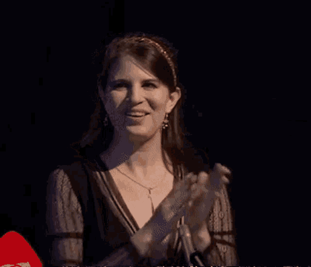 a woman wearing a headband and a necklace is smiling in a dark room